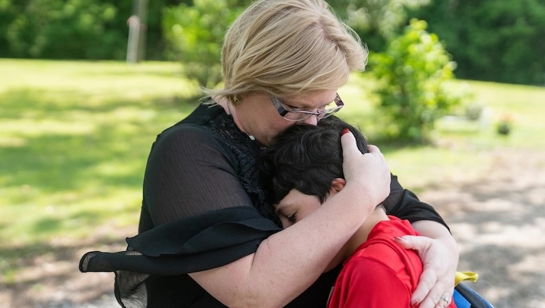 Blonde mom hugs young son with dark hair